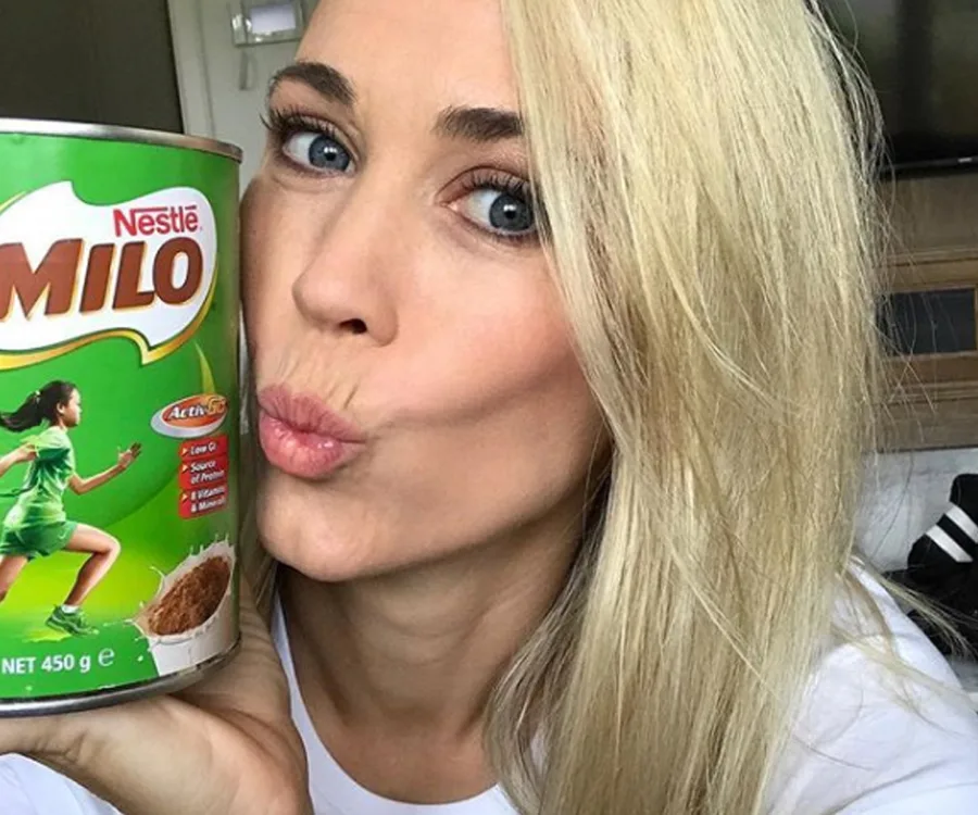 Blonde woman poses with a green Nestlé Milo tin, puckering her lips playfully.