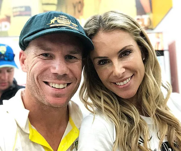 A man in an Australian cricket cap smiles alongside a woman with blonde hair.