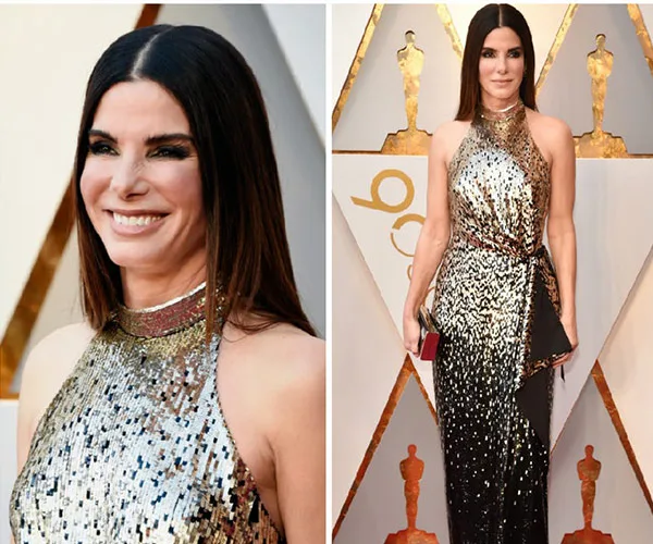 Sandra Bullock at an event in a shimmering halter-neck gown, posing and smiling on the red carpet.