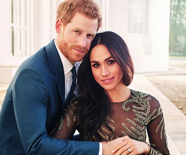 Couple embracing in formal attire, with the woman wearing a dress featuring leaf patterns and the man in a blue suit.