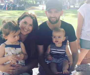 A family of four sitting outdoors, with a man, woman, and two children enjoying a sunny day.