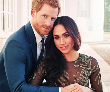 A couple posing together, with the man in a blue suit and the woman in a green embroidered dress.