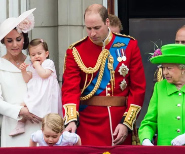 Family on a balcony, young children in the foreground, adults in formal attire, including a woman in bright green.
