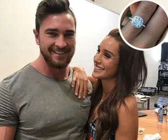 Couple smiling, with woman's hand showing an engagement ring; small inset of the ring close-up.