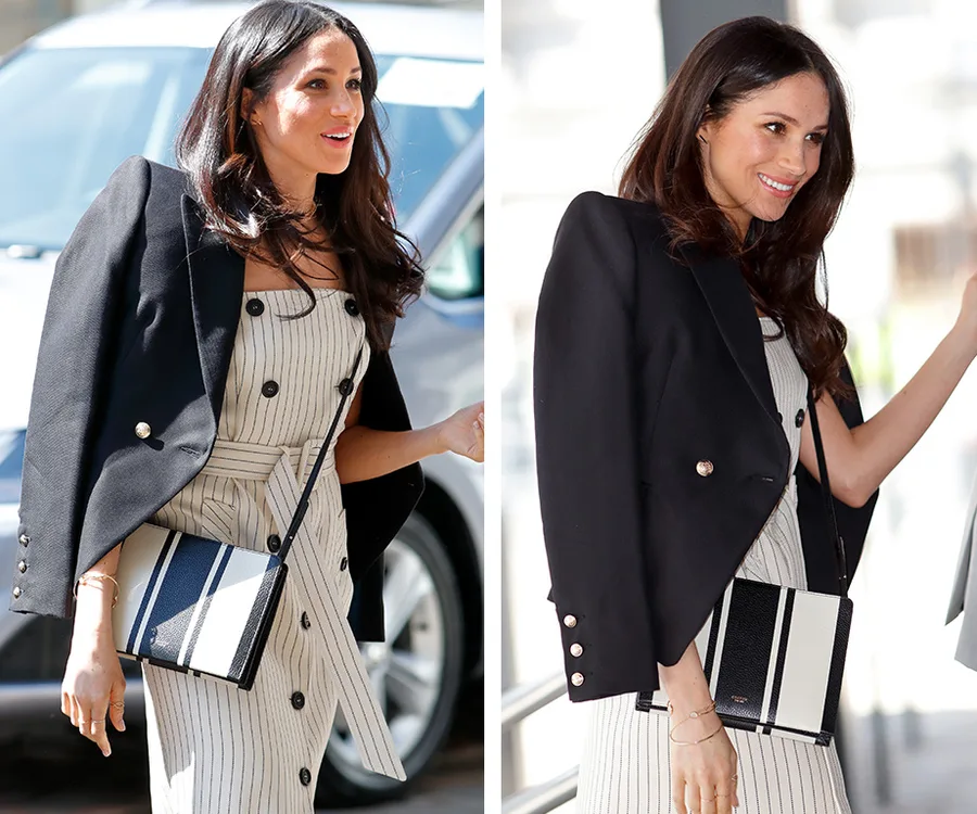 "Person in black blazer over striped dress, carrying a striped Oroton bag, smiling outdoors."