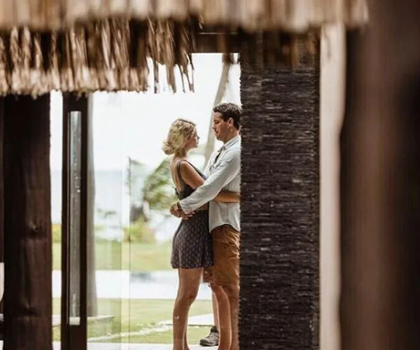 A couple embracing while standing in a doorway, overlooking a scenic outdoor view.