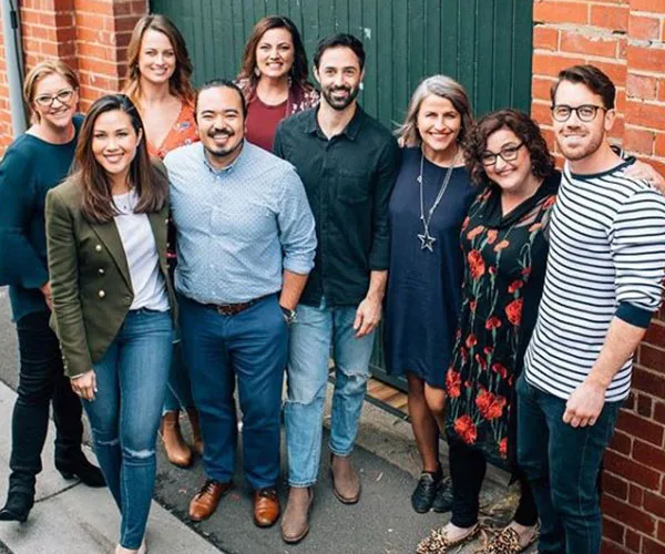 Group of MasterChef Australia winners smiling and standing together outside in casual attire.