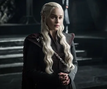 "Daenerys Targaryen with long braid in armor-like outfit, standing in a dimly lit room from Game of Thrones, Season 8."