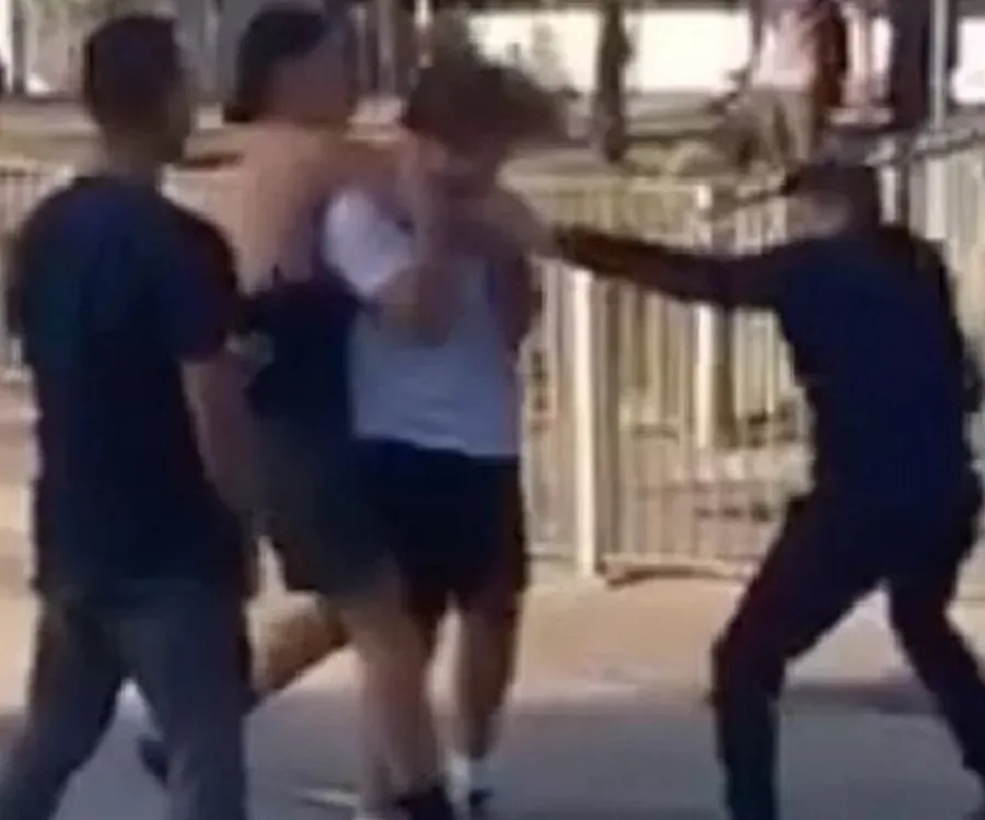 Group altercation involving four young males, with one being restrained and another appearing to wield an object.