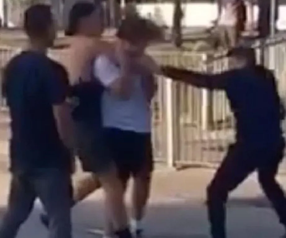 Group altercation involving four young males, with one being restrained and another appearing to wield an object.