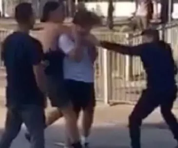 Group altercation involving four young males, with one being restrained and another appearing to wield an object.