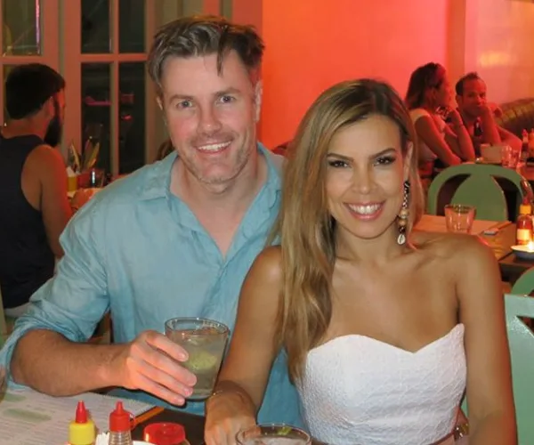 A smiling couple sitting at a restaurant table, each holding a drink.