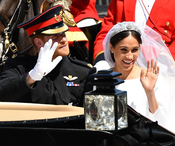 Prince Harry and Meghan Markle wave from a wedding carriage during their royal wedding procession.