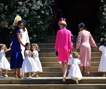 Guests and flower girls ascend steps, surrounded by floral decor, at Prince Harry and Meghan Markle's royal wedding.