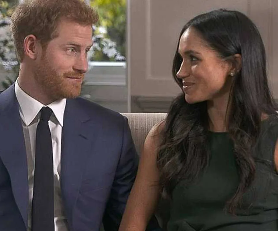 A couple sitting on a couch, smiling at each other during an interview.