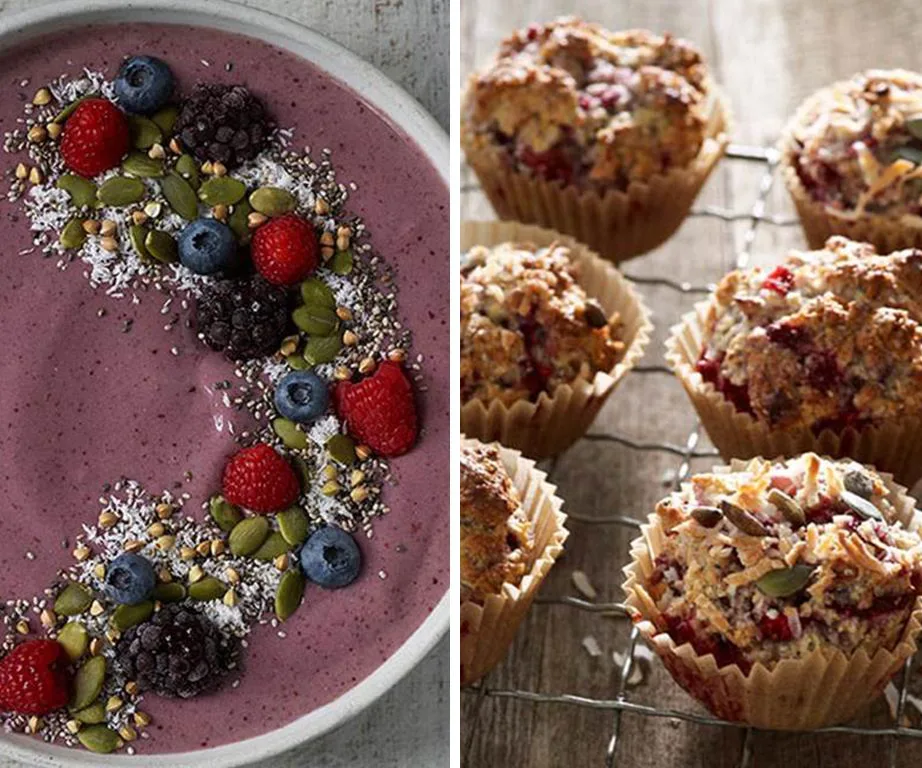 Berry smoothie bowl with seeds and fruit, and a rack of rustic berry muffins in paper cups on a wooden table.