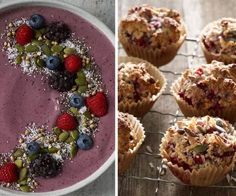 Berry smoothie bowl with seeds and fruit, and a rack of rustic berry muffins in paper cups on a wooden table.