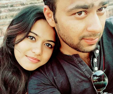 A couple taking a close-up selfie, both smiling slightly, with steps visible in the background.