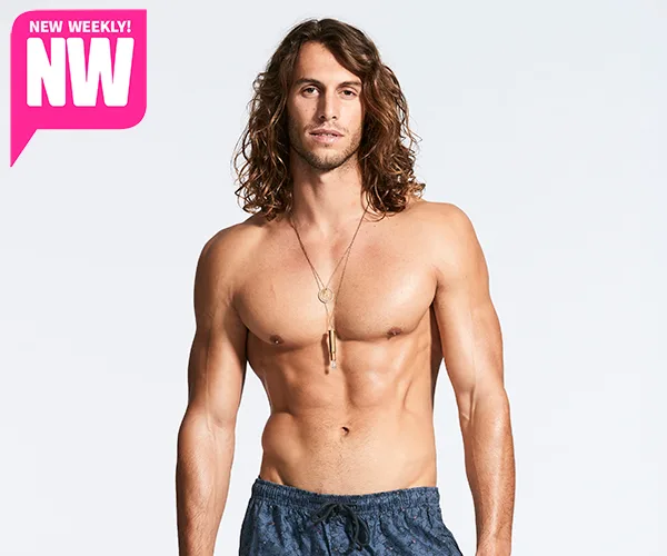 A shirtless man with long hair wearing a necklace and shorts, posing against a plain background with a "New Weekly" logo.