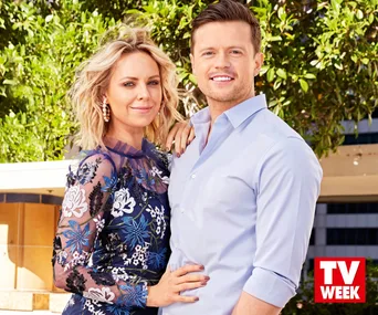 "Man and woman smiling in garden setting, both wearing formal clothes, with 'TV Week' logo in the corner."