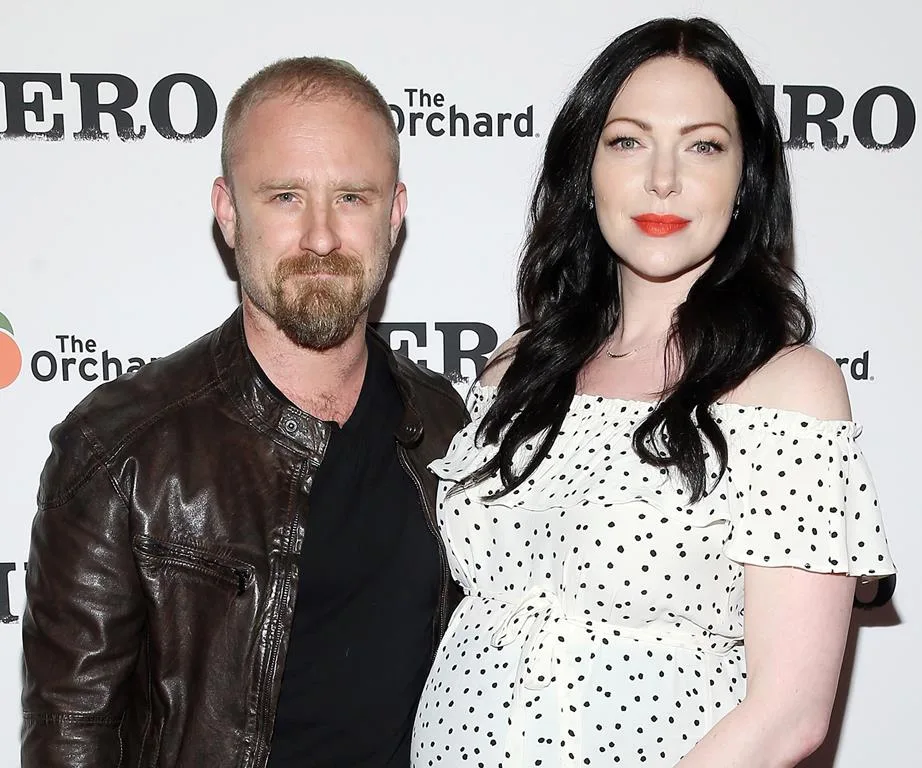 Laura Prepon and Ben Foster smiling at a red carpet event, Laura in a polka dot dress, Ben in a leather jacket.