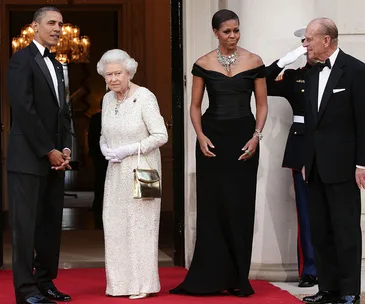 Four people in formal attire on a red carpet at a grand entrance.