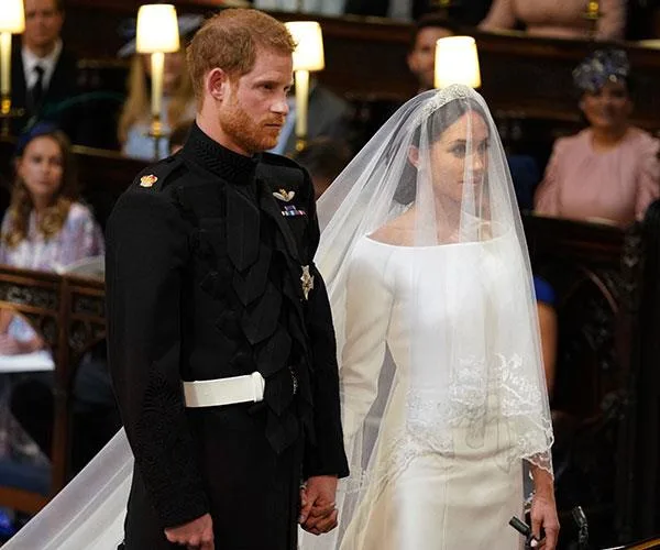 Royal wedding ceremony with a bride in a white gown and veil, and groom in military uniform in a church setting.
