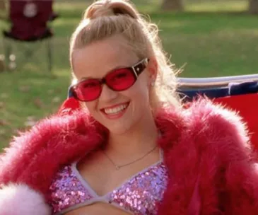 Elle Woods in a sparkly pink outfit and sunglasses, smiling outdoors from "Legally Blonde".