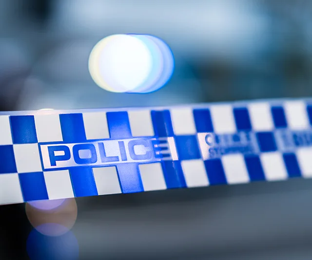 Police tape with the word "POLICE" in blue and white, blurred lights in background.