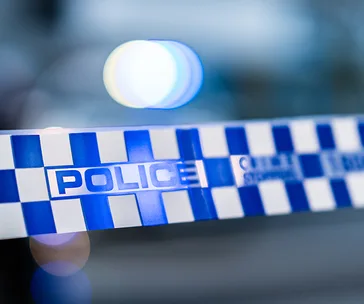 Police tape with the word "POLICE" in blue and white, blurred lights in background.