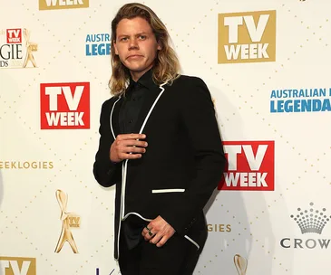 Singer Conrad Sewell at the Logie Awards in a black suit with white trim, posing on the red carpet.