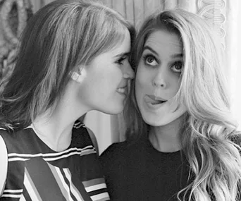 Two women smiling, one playfully sticking out her tongue, captured in a candid black-and-white photo.