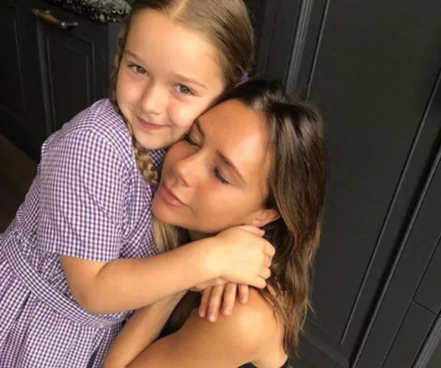 A woman embraces a young girl with braided hair, both appear happy and content.