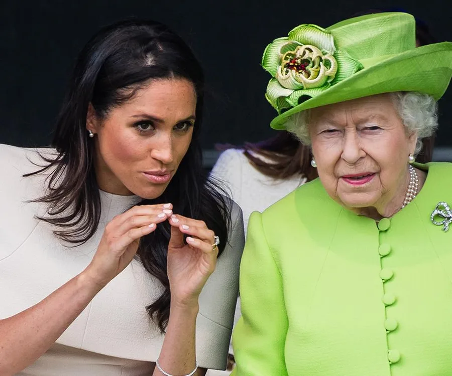 Two women sitting together, one in a light dress and the other in a bright green outfit with a matching hat.