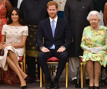 Meghan Markle, Prince Harry, and Queen Elizabeth seated at the Queen's Young Leaders Awards ceremony.