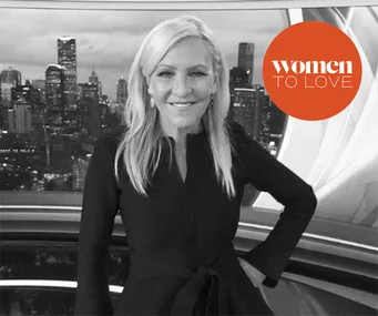 Woman in a black dress standing in front of a city skyline with "Women to Love" logo on the right.