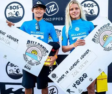 Two surfers holding prize checks at Billabong Junior Series 2018, surfer Zoe Steyn on right.