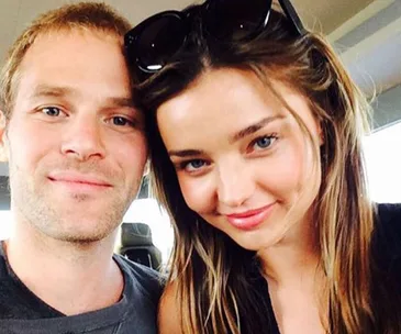 Two people smiling at the camera inside a vehicle.