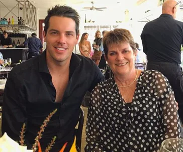 Two people smiling at a restaurant, a man in a black shirt and a woman in a polka dot blouse.