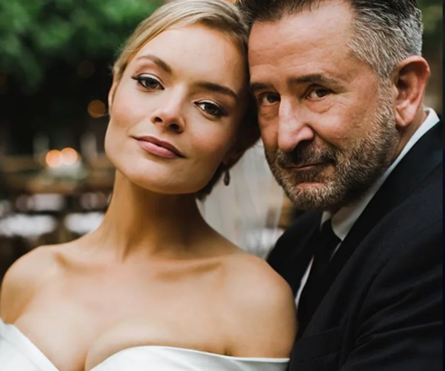 A couple on their wedding day, with the bride in a white gown and the groom in a suit, posing closely together.