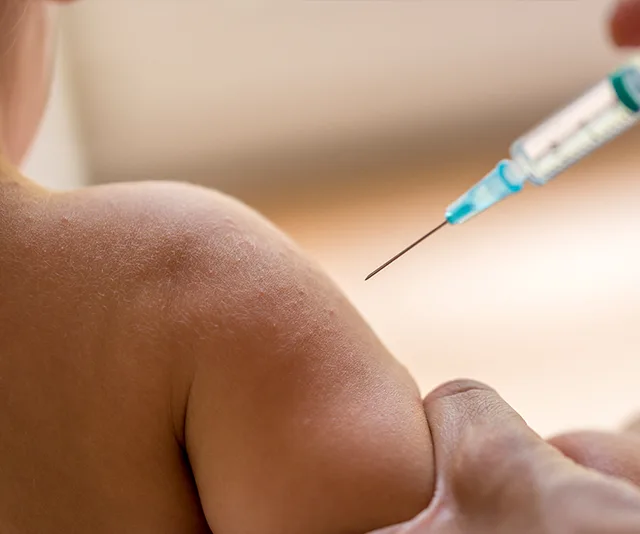 Child receiving a vaccination in the arm with a syringe.
