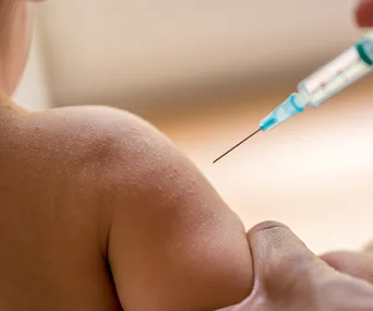 Child receiving a vaccination in the arm with a syringe.