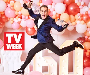 Jumping man in suit holds two awards against a colorful balloon backdrop, with "TV Week" logo visible.