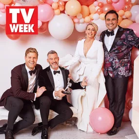 Group of four smiling people in formal wear with balloons and TV Week sign. One holds an award trophy.