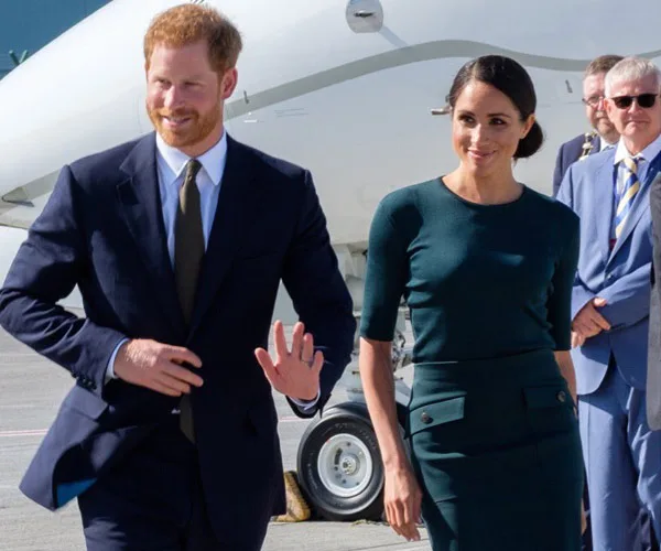 Prince Harry and Meghan Markle arriving at Dublin airport, smiling and greeting people.