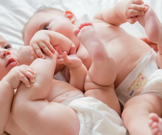Image of twin baby girls cuddling on bed.