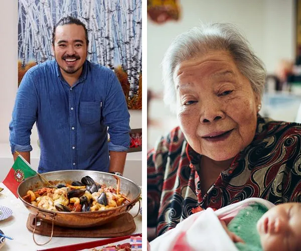 A man in a blue shirt stands by a seafood dish; an elderly woman smiles next to him, holding a baby.