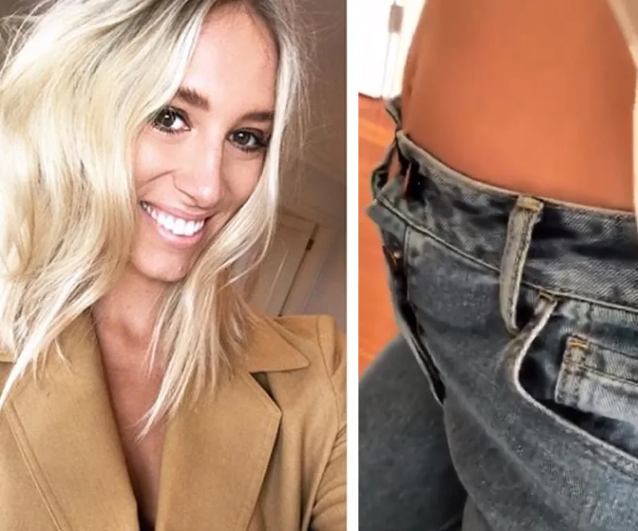 Blonde woman smiling in a tan coat; jeans fastened with a hair tie for extra room.