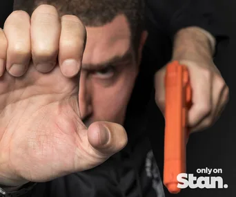 A man holding a toy gun and making a hand gesture, with "only on Stan" text displayed.