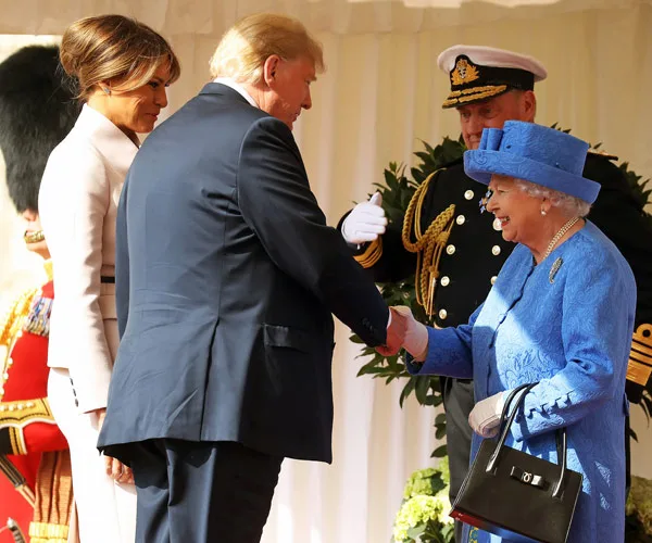 Donald Trump shaking hands with Queen Elizabeth II, with Melania Trump nearby, during a formal event.